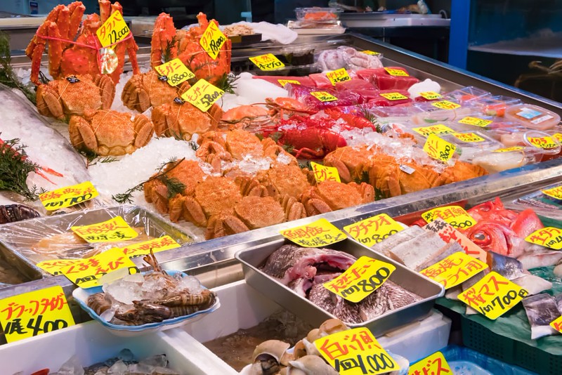 A selection of seafood on ice with price labels at the Tsukiji Fish Market Outer Market in Tokyo, Japan