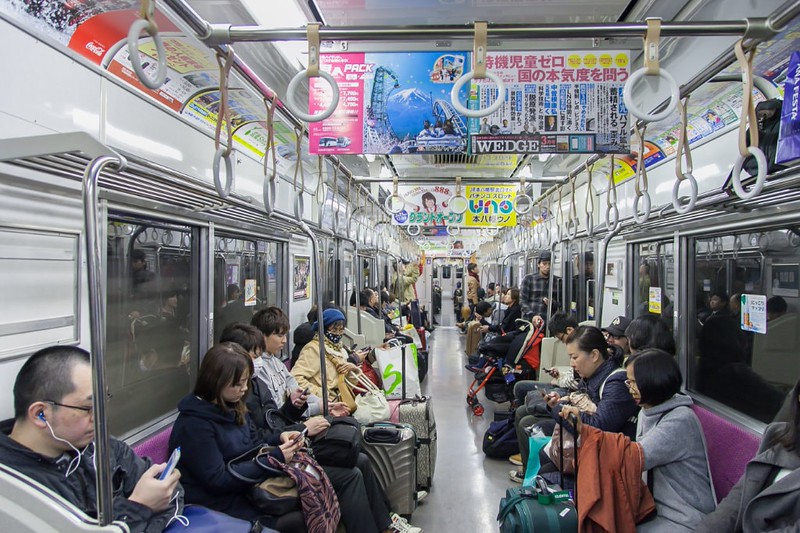 Travellers with luggage sit on a subway train from Haneda International Airport, Tokyo