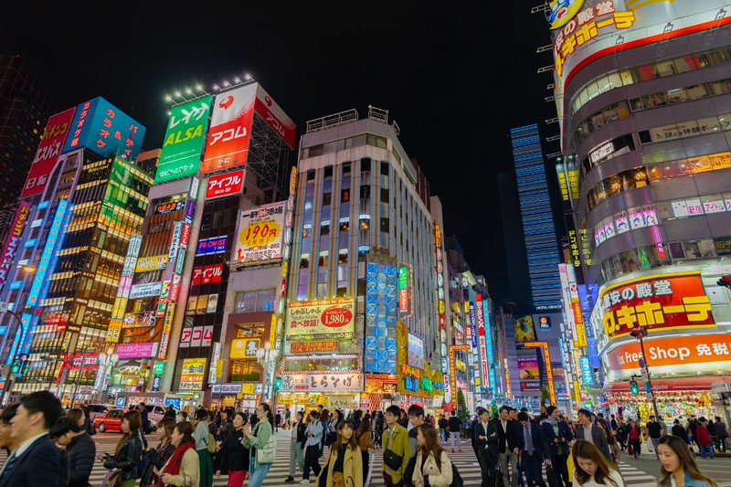 A crowd of people on the famous Shibuya Crossing in Tokyo surrounded by neon lights A crowd of people on the famous Shibuya Crossing in Tokyo surrounded by neon lights