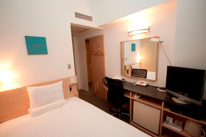 Simple double room in the Smile Hotel Nihombashi Mitsukoshimae, Tokyo, Japan, with bed, desk and mirror, fridge, and TV