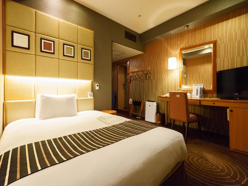 Double bed and desk area in a guest room in Tokyo’s Sotetsu Fresa Inn Higashi Shinjuku hotel