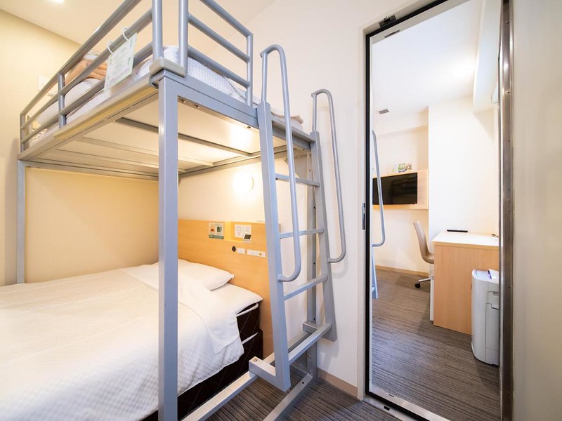 Cabin-style bedroom with single and loft bed, and view of desk and TV in adjoining room in the Super Hotel Asakusa, Tokyo, Japan