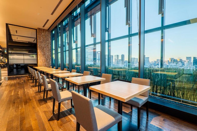 Rows of tables by the tall, wall-length window overlooking Tokyo in The Blossom Hibiya hotel restaurant Rows of tables by the tall, wall-length window overlooking Tokyo in The Blossom Hibiya hotel restaurant