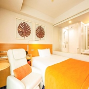 A guest room in the Remm Hibuya hotel, Tokyo, Japan, with orange interiors, bed, shower room, and massage chair