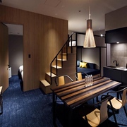 A superior quad room in the Hundred Stay Tokyo Shinjuku hotel with dining table, kitchen area, and stairs to a loft bed