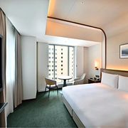 Big comfortable twin beds in a corner room of Tokyo’s Marunouchi Hotel with a nighttime view of the city