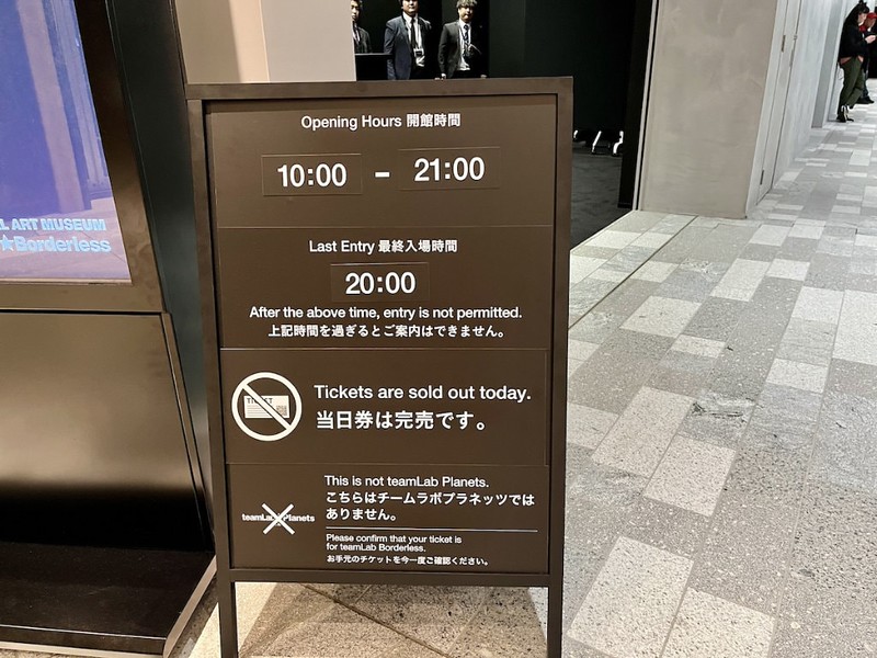 A sandwich board with ticket information outside teamLab Borderless in Azabudai Hills