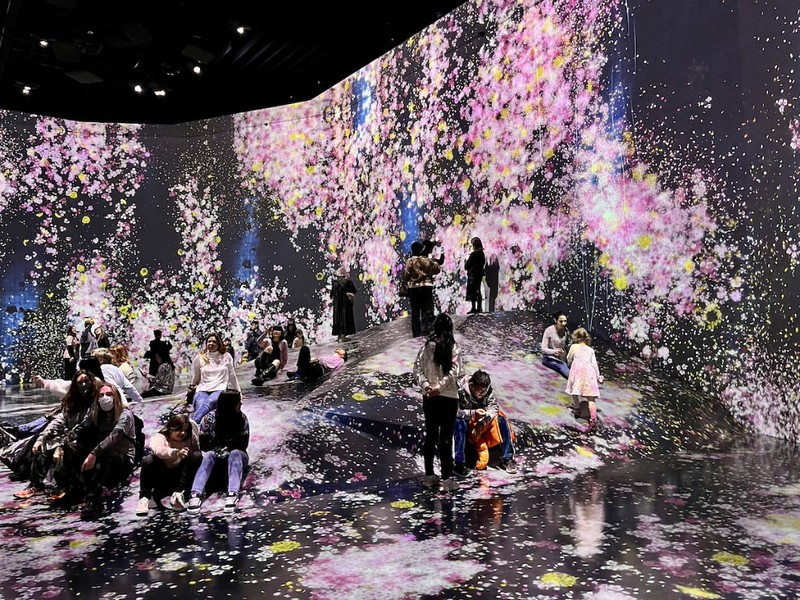 Families enjoy clambering around the raised rock-shaped platform in a room in the teamLab Borderless experience