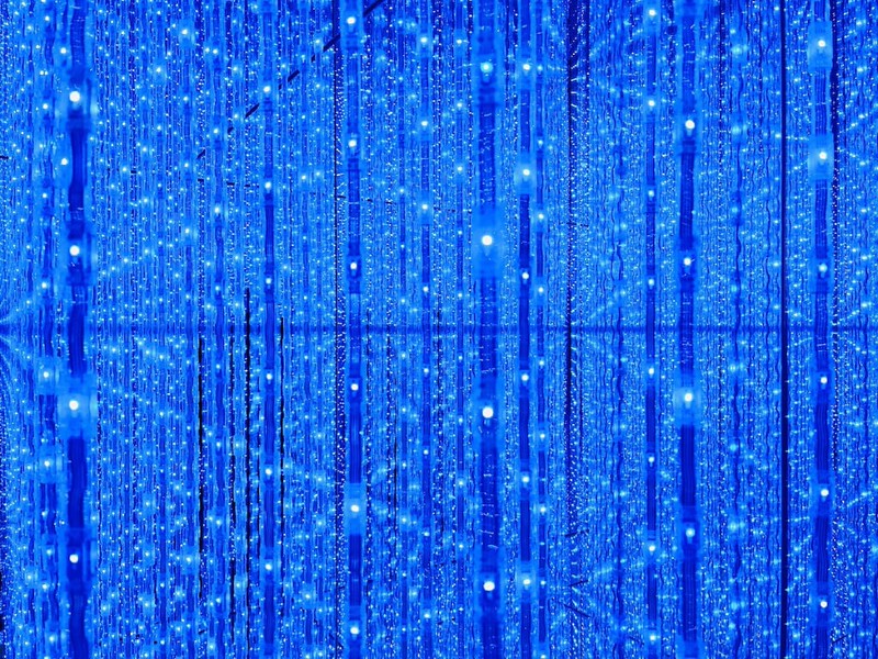 A teamLab Borderless infinity room full of thousands of strands of shimmering LED lights that change colour over time