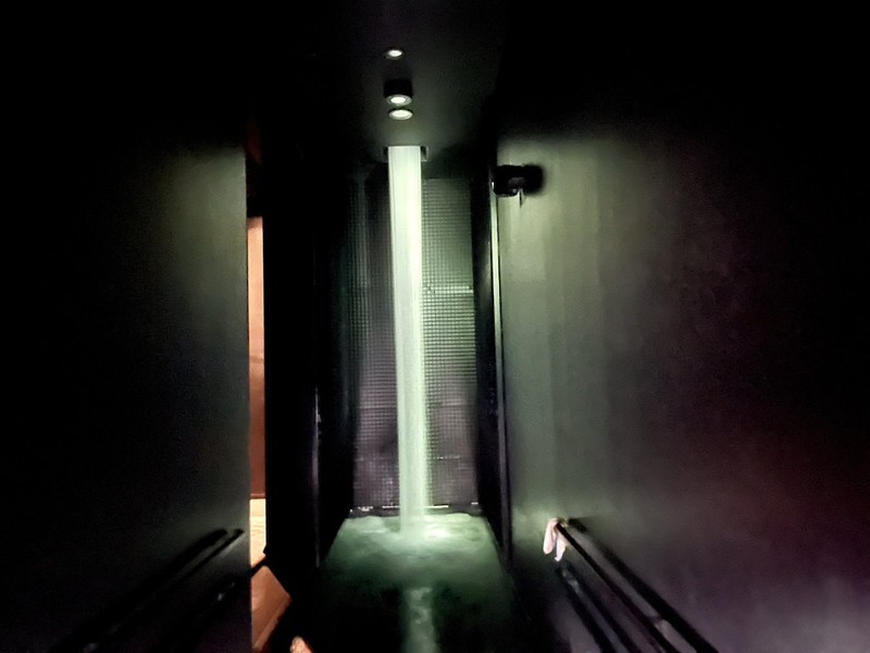 An exhibit in the teamLab Planets exhibition in Japan, Tokyo, featuring an illuminated pillar of water at the end of a corridor