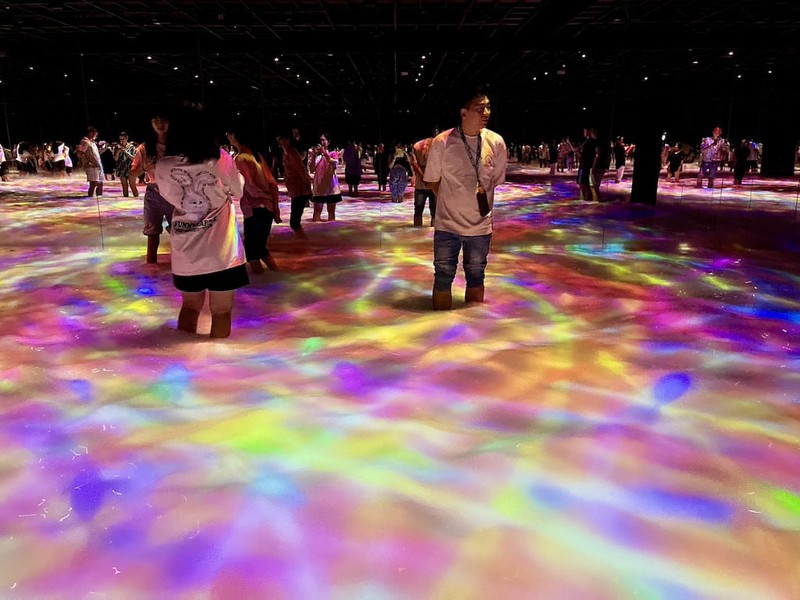 Visitors wade through shimmering, multi-colored water in the teamLab Planets exhibition in Tokyo, Japan