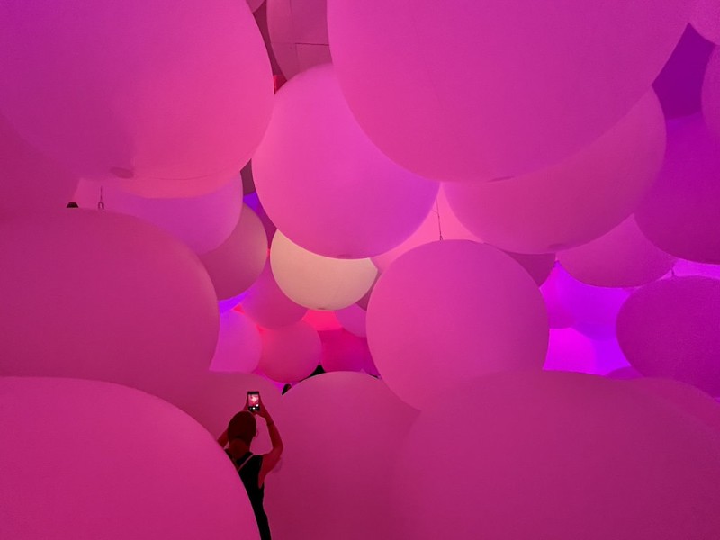 A visitor takes a photo, whilst surrounded by huge, soft, illumated lilac globes in the teamLab Planets exhibition in Tokyo, Japan