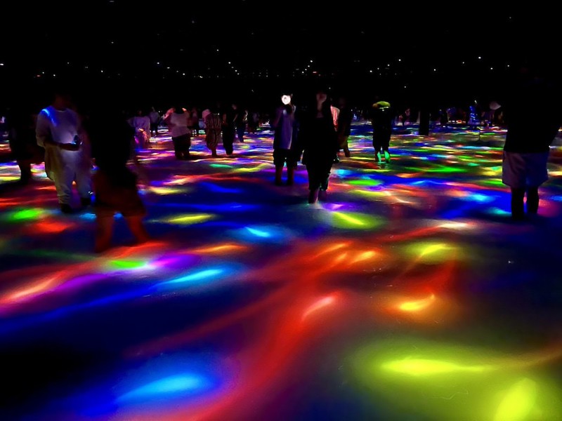 Visitors experience the multi-colored dance of abstract koi carp on the floor of the teamLab Planets exhibition in Tokyo, Japan