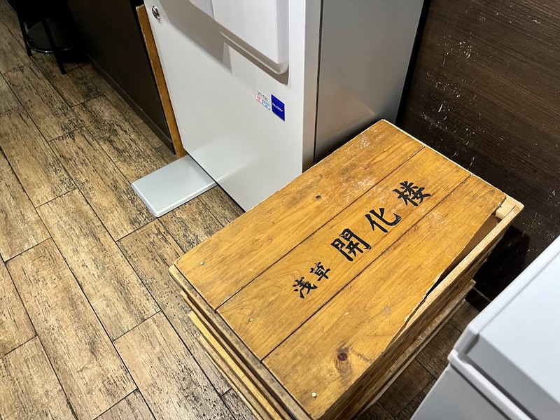 View of the floor of a Tokyo ramen restaurant with a fridge unit and a wooden crate containing noodles freshly delivered from Asakusa Kaikarou