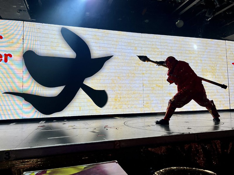 A ninja at Samurai Restaurant Time wielding a huge calligraphy brush paints on the screen behind him