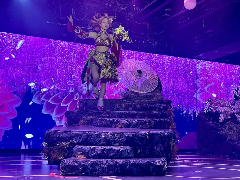 A performer in a gold and red outfit descends a rocky staircase at Samurai Restaurant Time